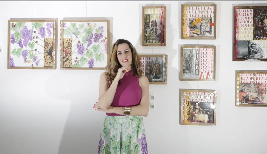 Pri Lorusso standing in front of her framed artworks at an exhibition.