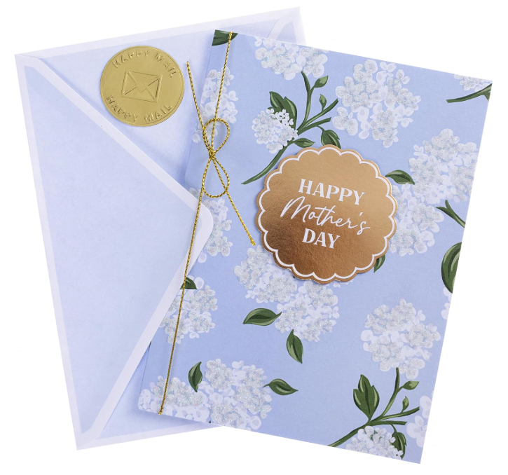 Handmade Mother's Day greeting card with lilac and hydrangea floral design and a gold badge, shown with a matching envelope.
